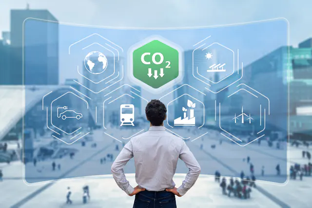 Geschäftsmann vor digitalen Symbolen zur CO₂-Reduktion