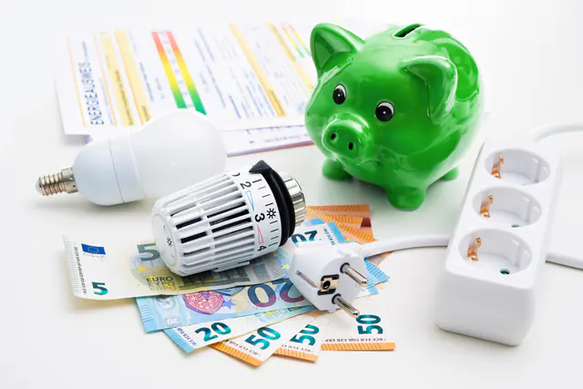 Sparschwein, Heizkörperthermostat und Geldscheine auf einer Energierechnung